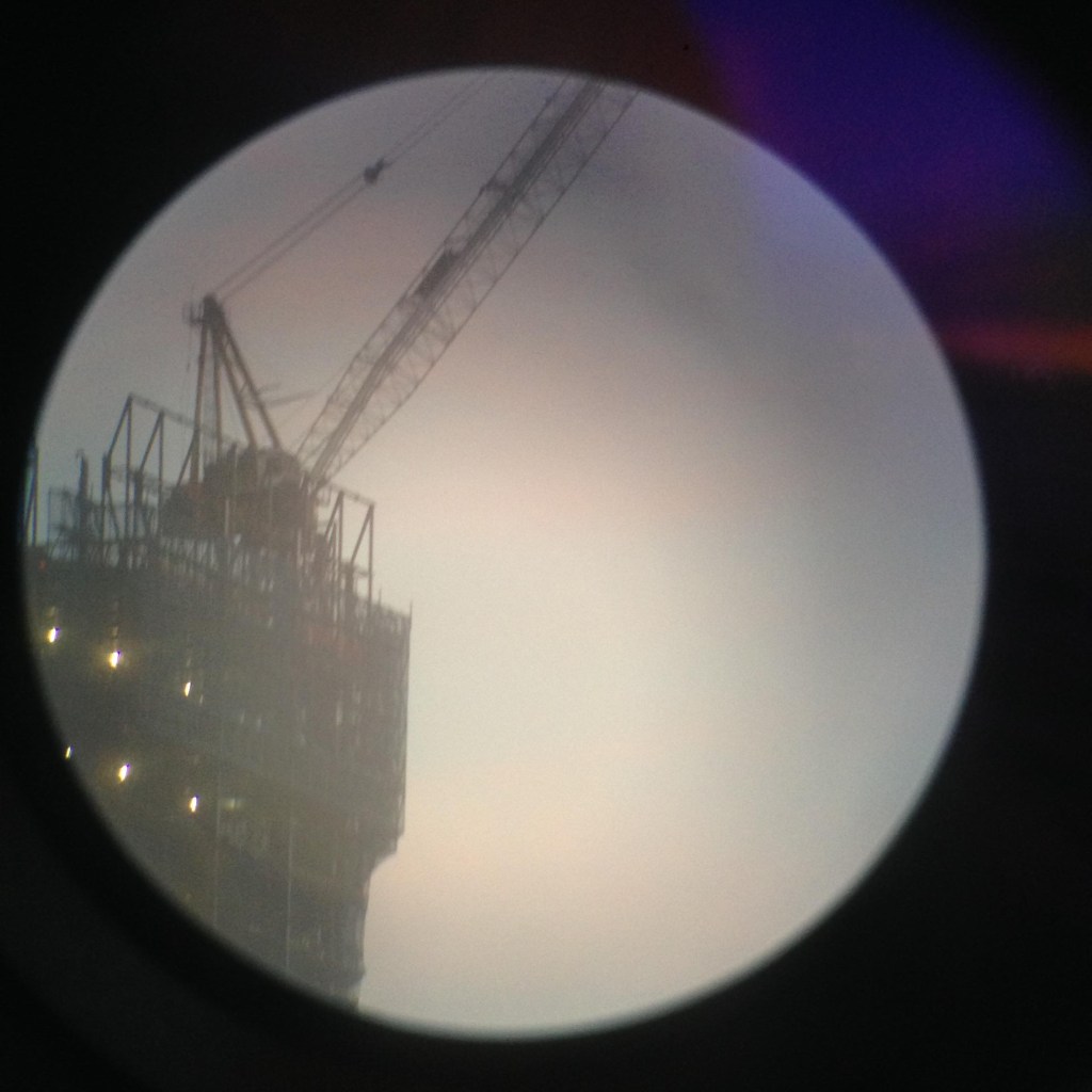 Digital image of a construction crane taken on an iPhone 6, shot through monocular.