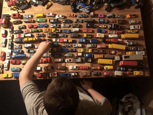Overhead view of Logan playing with colourful toy cars on tabletop