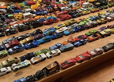 colourful toy cars lined up in rows on wooden tabletop