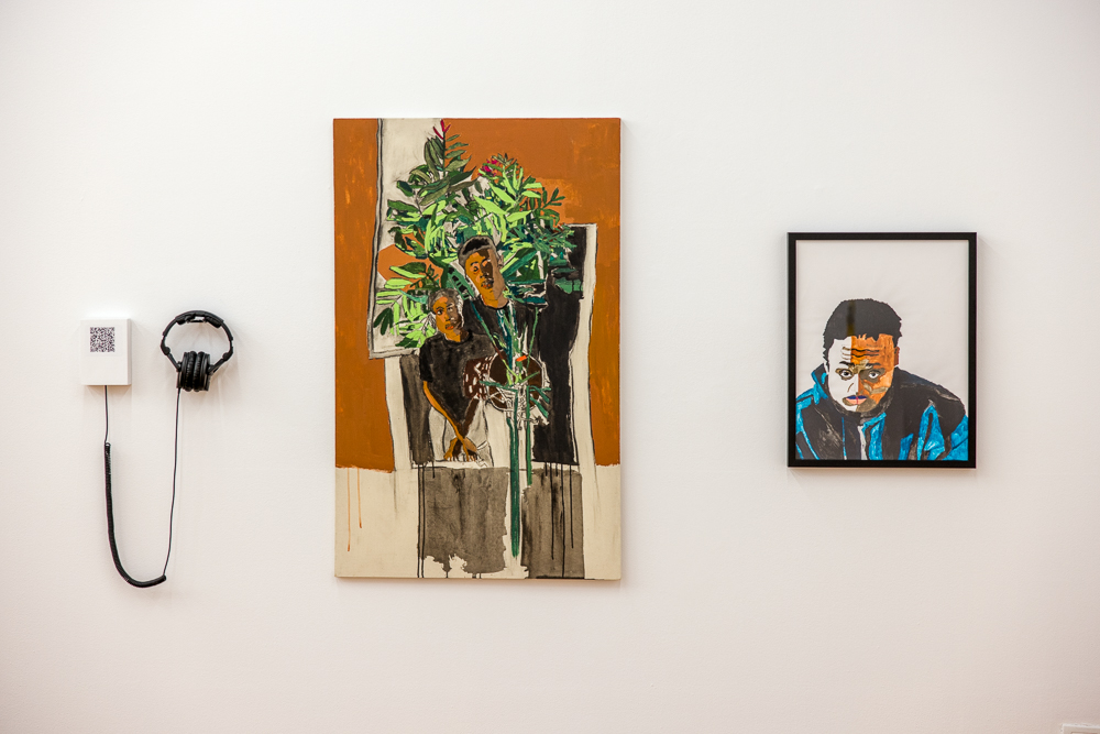 Straight-on view of two artworks hanging on a wall and a set of headphones with audio track. 